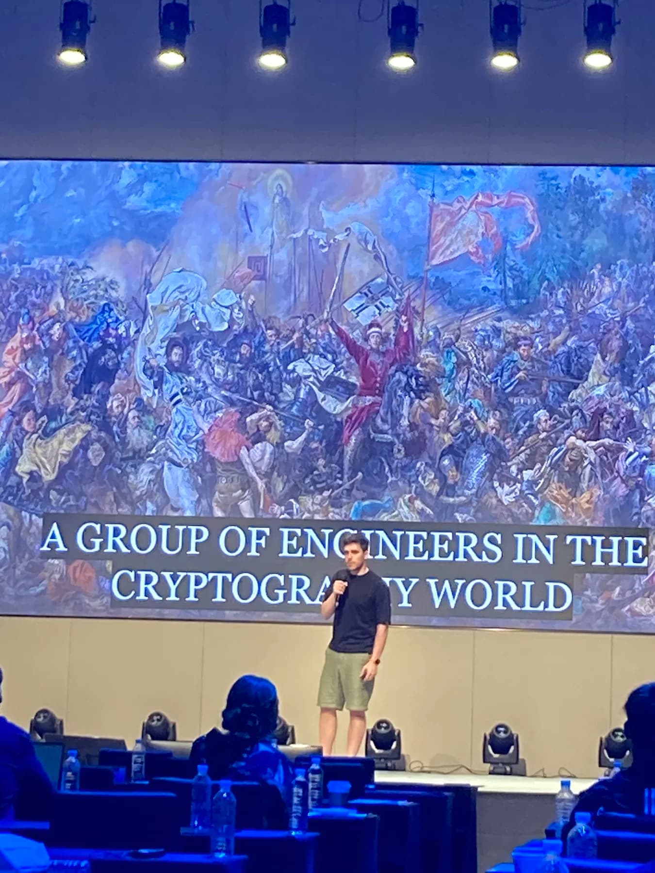 A speaker at ETH Seoul standing in front of a slide that reads A group of engineers in the cryptography world.