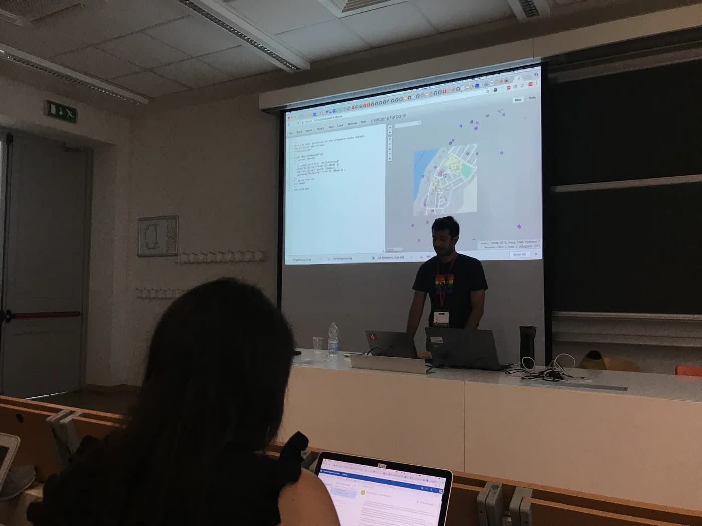 A presenter demonstrating an OpenStreetMap editing workflow on a projected map.